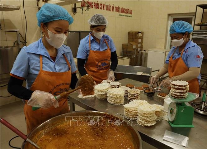 Workers make 'cu do' - a candy made of roasted peanuts and molasses and covered with rice pancakes. The candy is a three-starred OCOP product of the central province of Ha Tinh. (Photo: VNA)