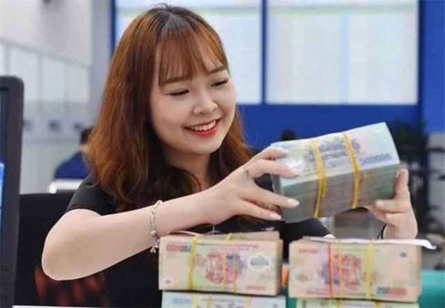 A bank teller counts money at a transaction office in Hanoi. If banks increase credit without control measures, the banking system may return to a state of overheating credit growth like before the 2011 period. (Photo: cafef.vn)