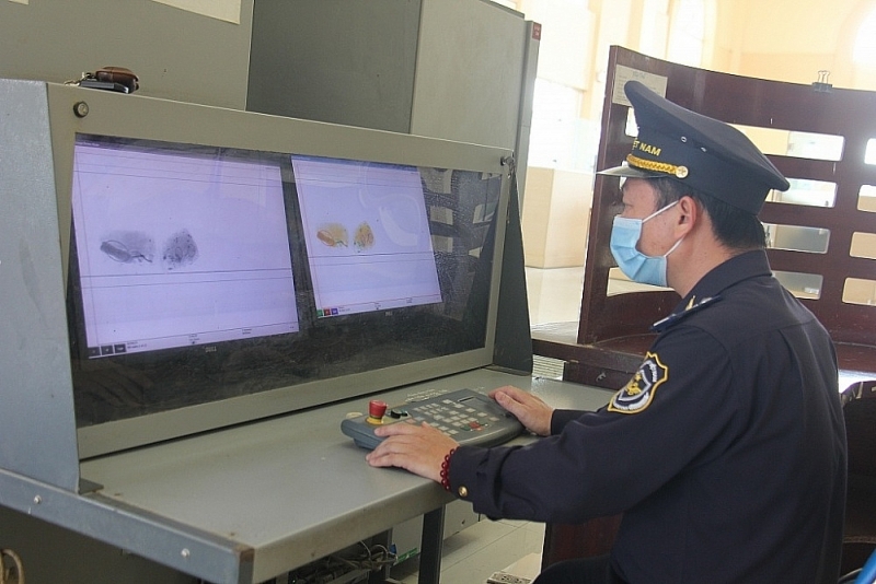 Customs officers at Tinh Bien international border gate check luggage through scanners. Photo: T.H