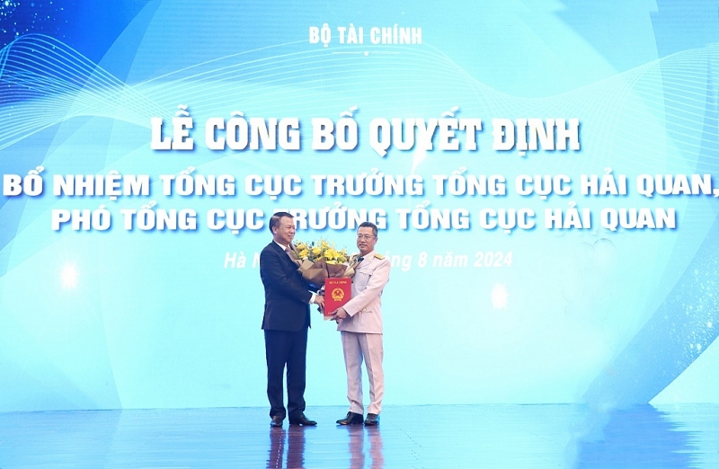 Deputy Minister Nguyen Duc Chi presents th appointment decision and flowers to congratulate the new Deputy General Director Au Anh Tuan. Photo: Quang Hung.